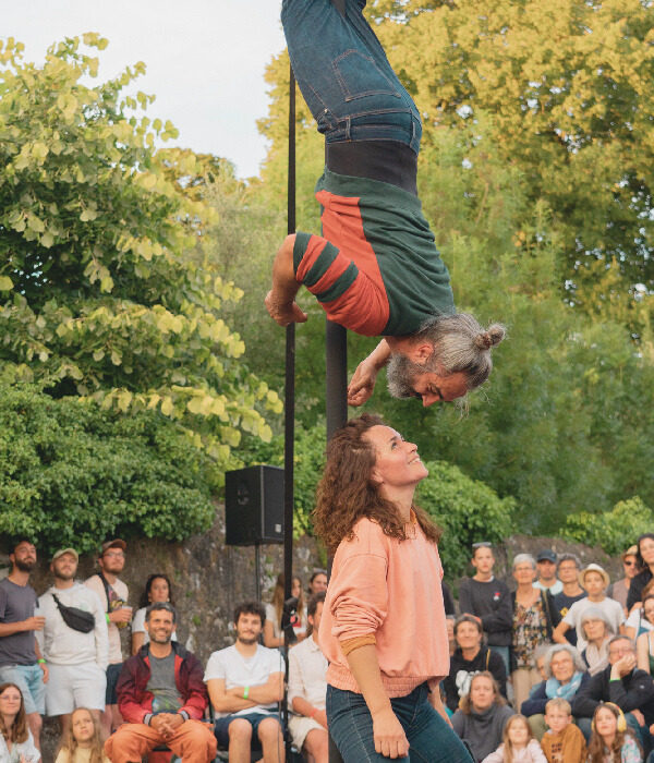 Laisse-moi is a Contemporary Circus show on Chinese Miguel Rubio, upside down, hanging from the pole, looking at Nely Carrasco standing.