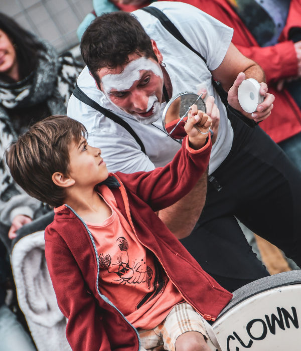 Circus clown show and street performance in Improlocura.Agro the clown putting on makeup with the help of a child during the mime show. Luca Della Gatta