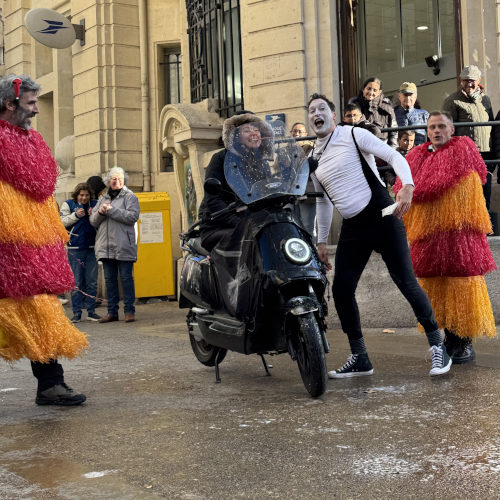 Car wash by Agro the Clown. Agro alongside two spectators dressed as car wash rollers stopping a motorcycle. Luca Della Gatta