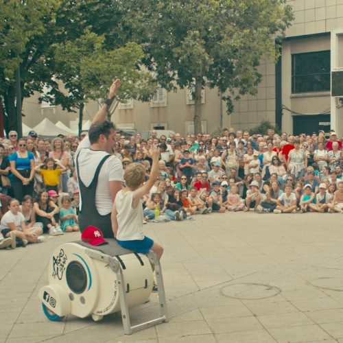 ImproLocura is a physical theater show. Luca Della Gatta. Agro the clown waving with a child spectator, with the audience in the background