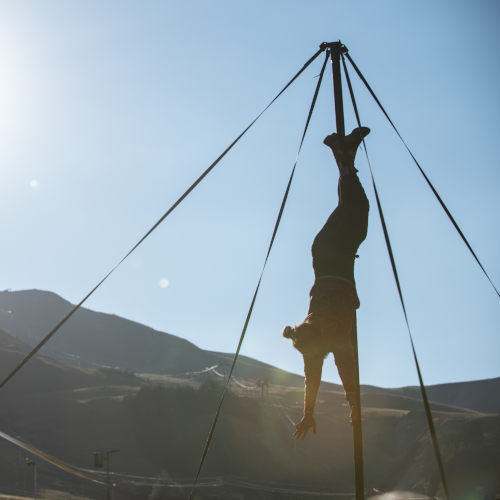 Playground - Chinese Pole Acrobatics Show. Miguel Rubio on the pole with mountains background