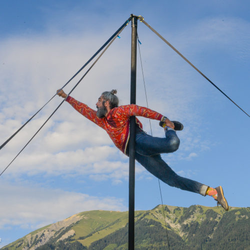 Playground - Chinese Pole Acrobatics Show. Miguel Rubio superman style on the pole with mountains background